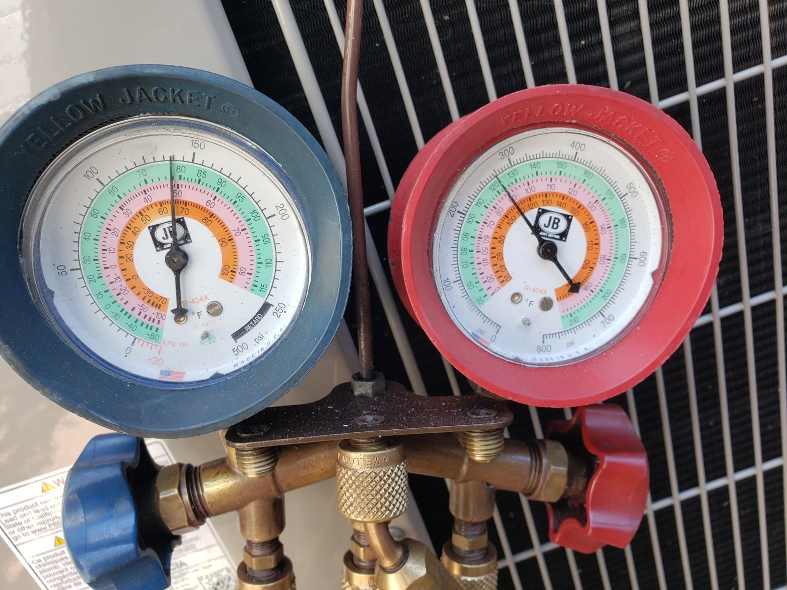 Refrigerant gauges on a condenser. Refrigerant charge is one of the measures a California rater verifies on many HVAC change-outs.